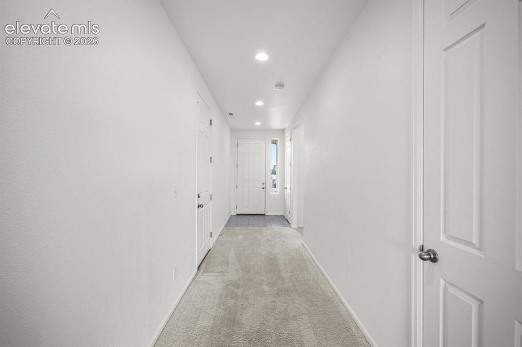 Image 4 of 25: Bright hallway featuring recessed ceiling lighting, white textured drywall,