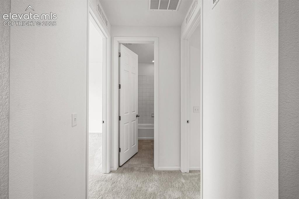 Image 5 of 25: Bright hallway featuring clean white walls, recessed ceiling lighting, and