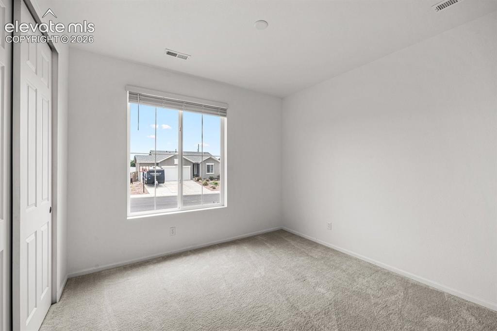Image 6 of 25: Neutral-toned carpeting, white walls, and a large window with blinds
