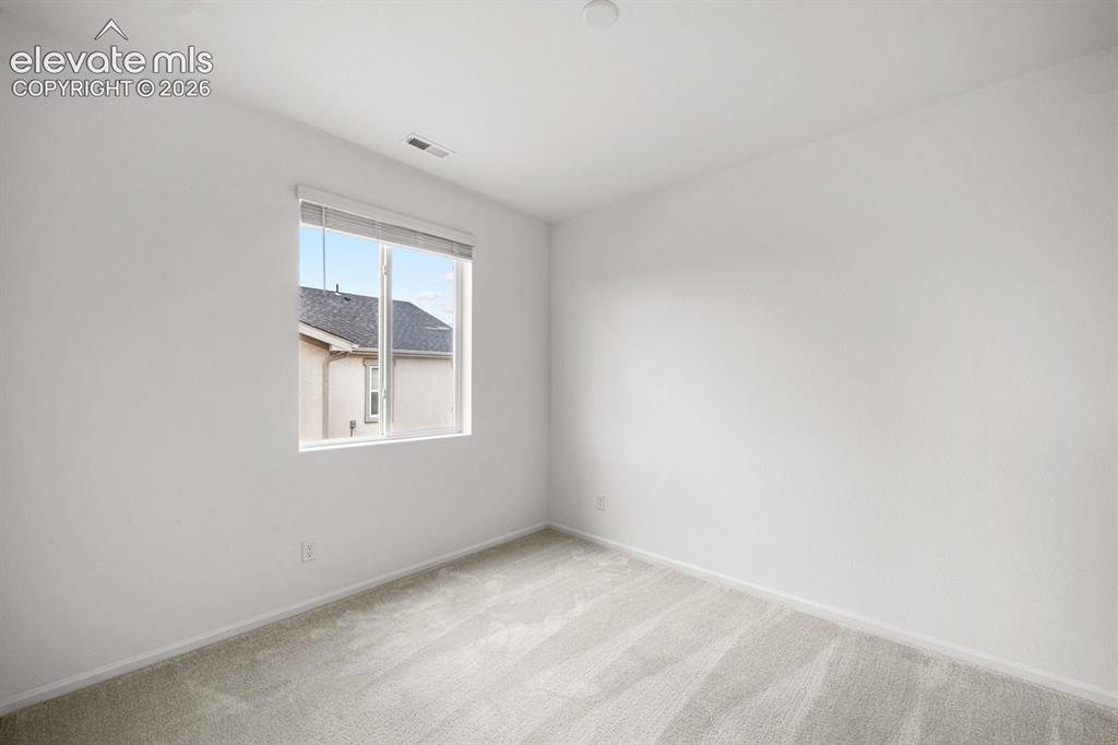 Image 7 of 25: Light-toned wall-to-wall carpeting, white painted walls, and a single windo