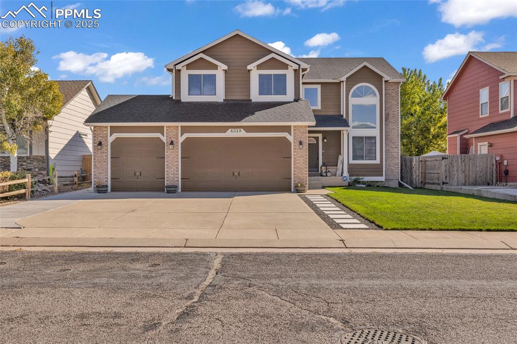 Caption: Traditional home with driveway, brick siding, and a shingled roof