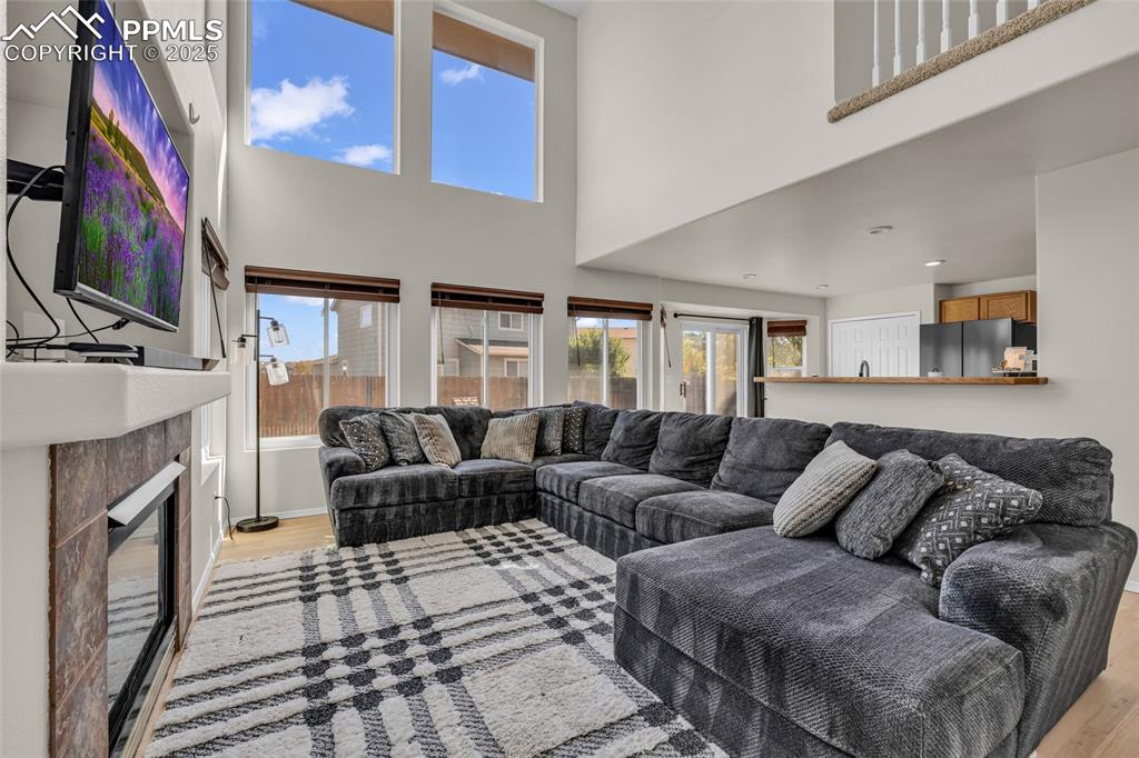 Image 12 of 40: Living area featuring light wood-style floors, a towering ceiling, and a gl