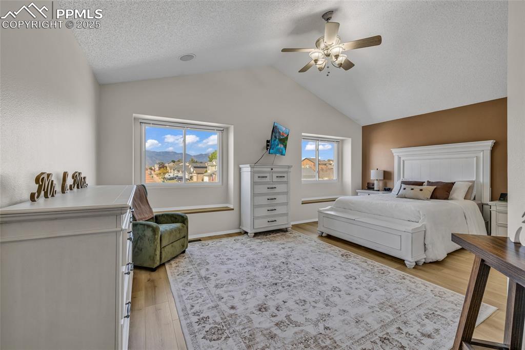 Image 13 of 40: Bedroom with light wood-type flooring, ceiling fan, vaulted ceiling, and a