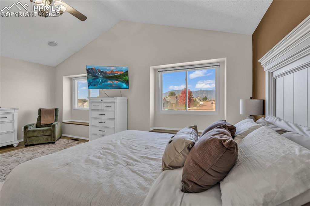 Image 15 of 40: Bedroom with a ceiling fan, vaulted ceiling, and wood finished floors