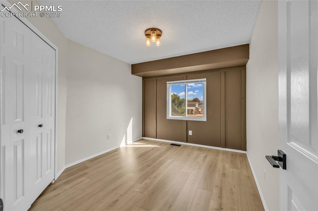 Image 18 of 40: Unfurnished bedroom with a textured ceiling, a closet, and light wood-style