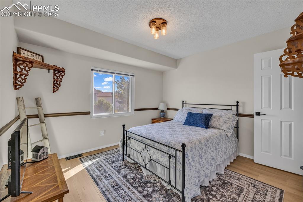 Image 20 of 40: Bedroom featuring a textured ceiling and light wood-style flooring