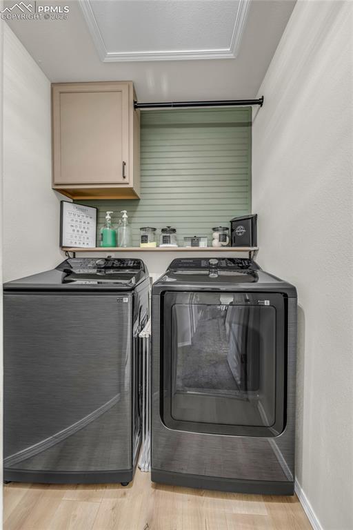 Image 21 of 40: Laundry area featuring light wood-type flooring, washer and dryer, and cabi