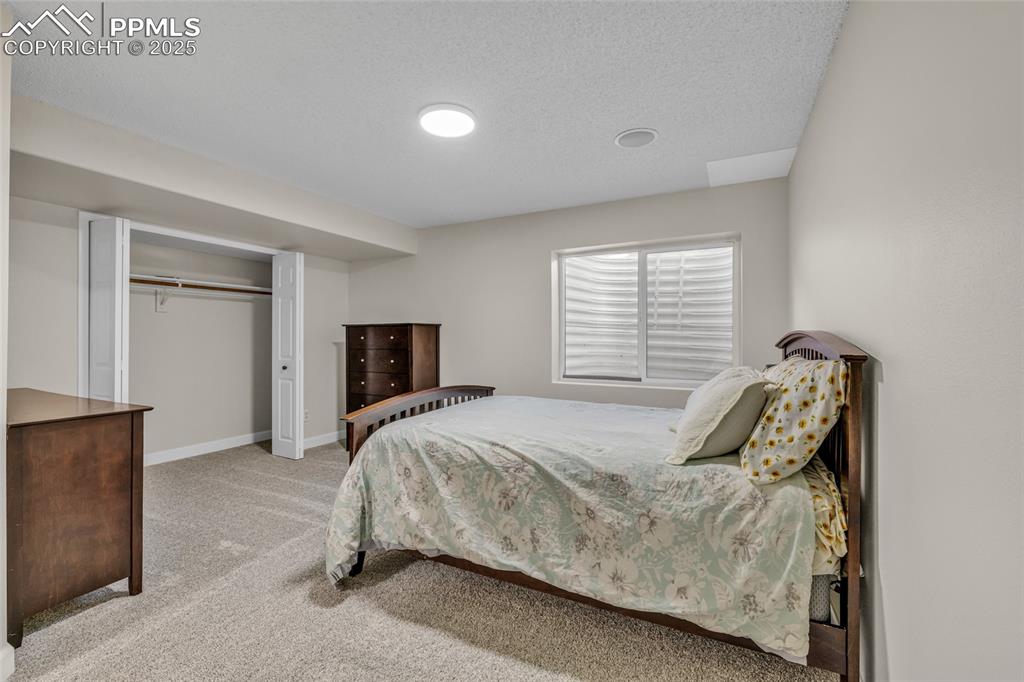 Image 28 of 40: Bedroom with light colored carpet, a closet, and a textured ceiling