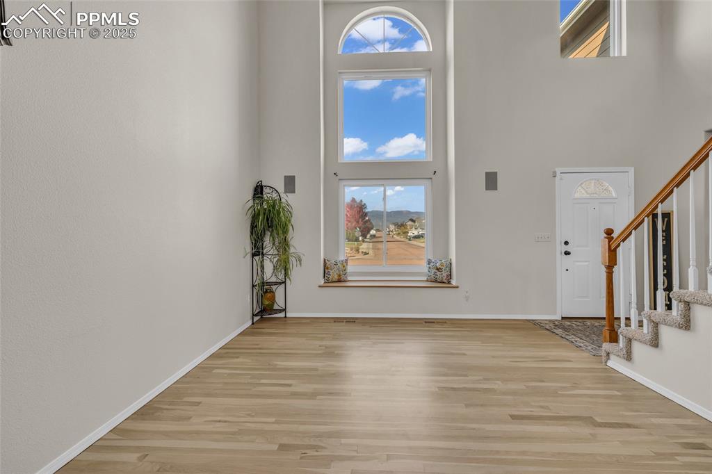 Image 3 of 40: Entrance foyer with stairs, a towering ceiling, and light wood-style floori