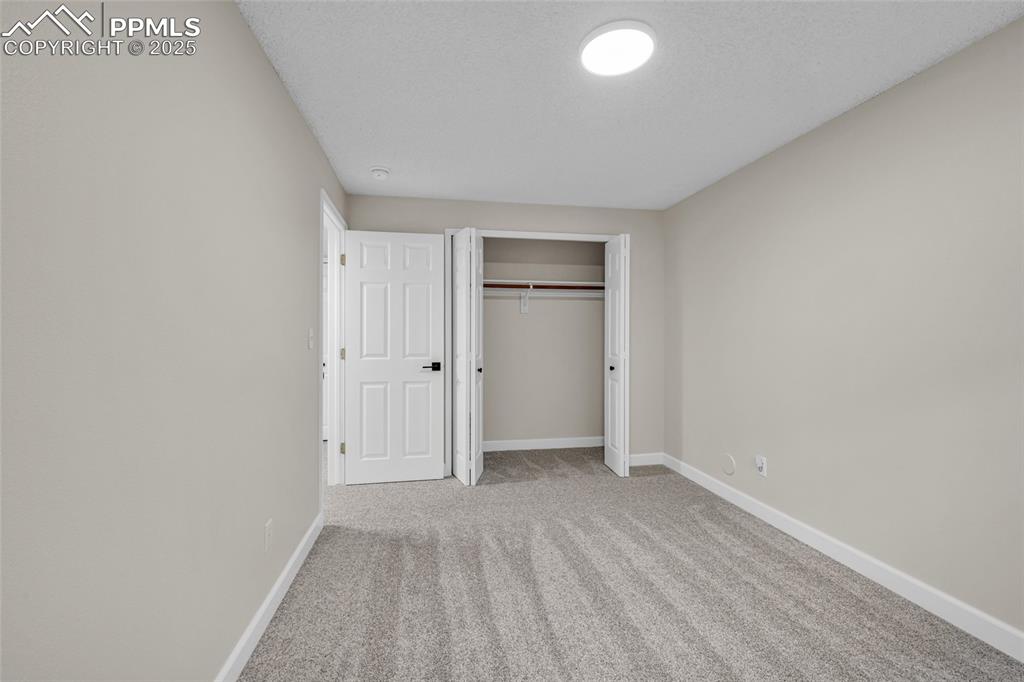 Image 30 of 40: Unfurnished bedroom featuring light colored carpet, a closet, and a texture