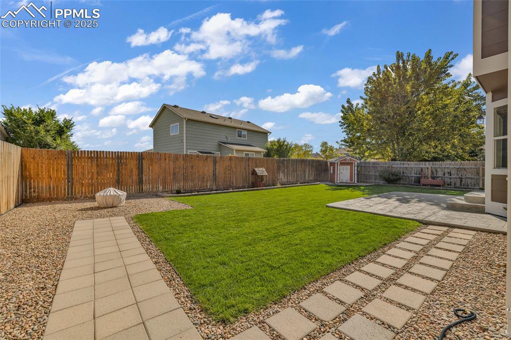 Image 33 of 40: Fenced backyard with a patio area and a shed