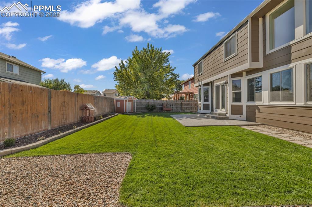 Image 34 of 40: Fenced backyard featuring a shed and a patio