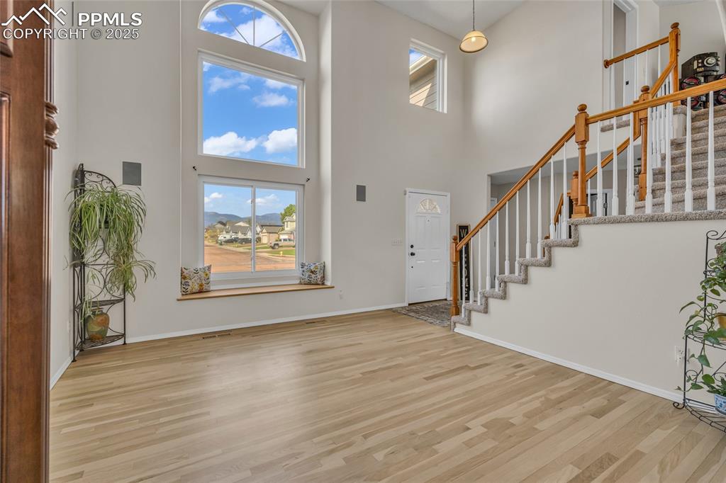 Image 4 of 40: Foyer featuring stairs, a towering ceiling, and light wood finished floors
