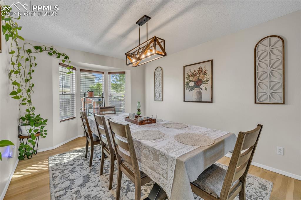 Image 6 of 40: Dining room featuring light wood finished floors and a textured ceiling