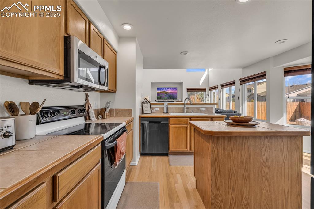 Image 7 of 40: Kitchen with electric stove, light wood-style flooring, stainless steel mic