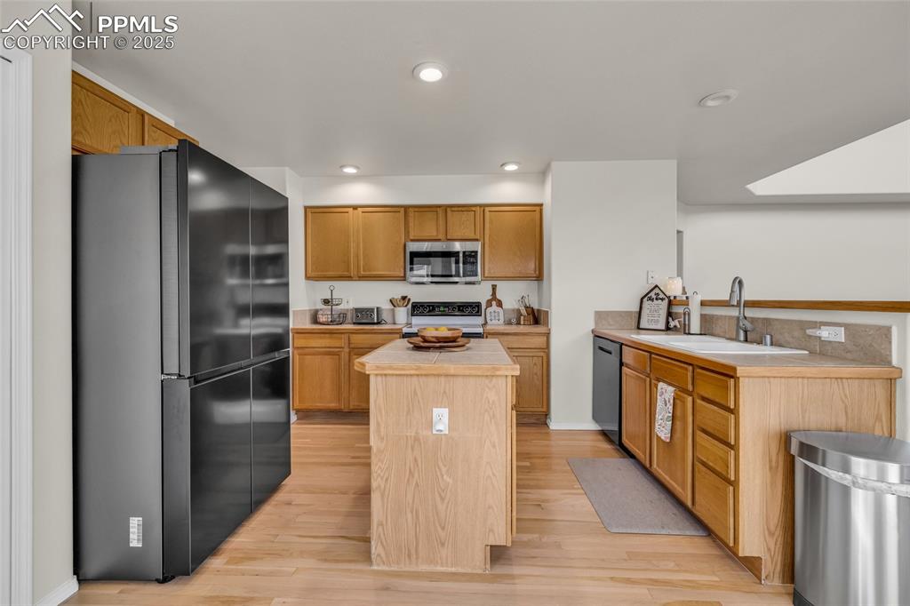 Image 8 of 40: Kitchen featuring stainless steel appliances, a center island, light wood-s