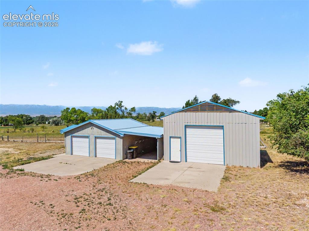 Image 15 of 50: Shed w/ electricity, 2-car garage, carport, RV garage/workshop.
