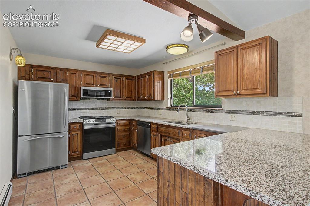 Image 21 of 50: Spacious kitchen with tile floor, natural gas range, granite counters, and