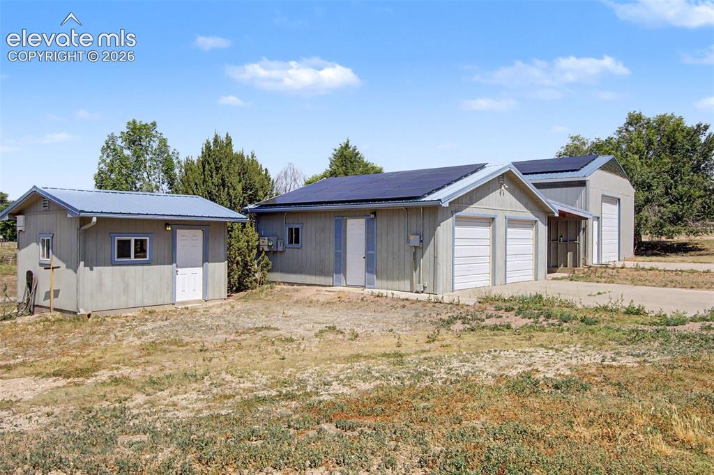Image 36 of 50: Shed w/ electricity, 2-car garage, carport, RV garage/workshop.