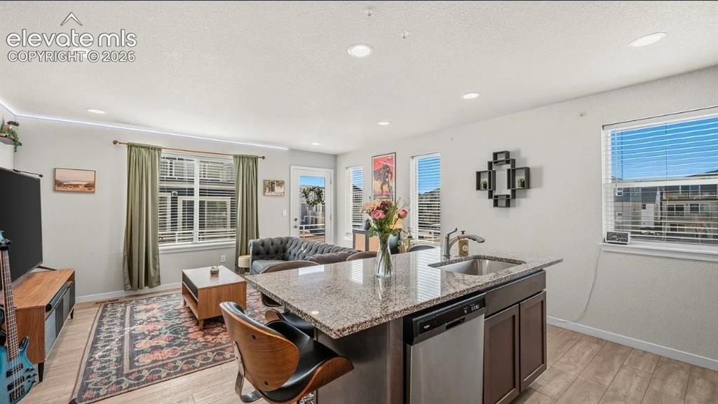 Image 10 of 22: Open-concept kitchen and living area featuring a large island with stone co