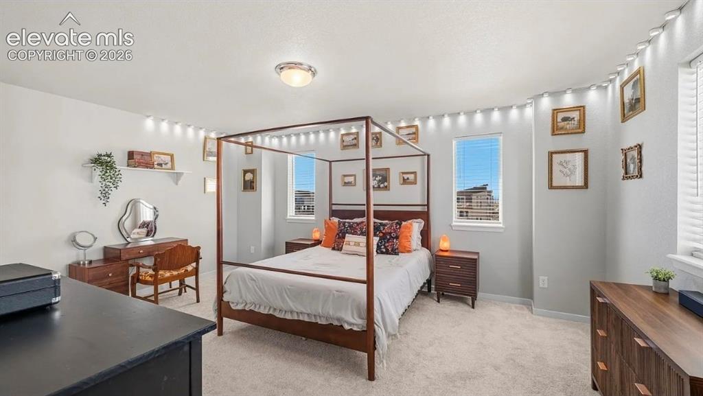 Image 18 of 22: Spacious primary bedroom featuring a four-poster bed frame, dual nightstand