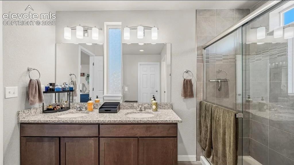 Image 20 of 22: Spa-inspired primary bathroom featuring a dual-sink vanity with speckled qu