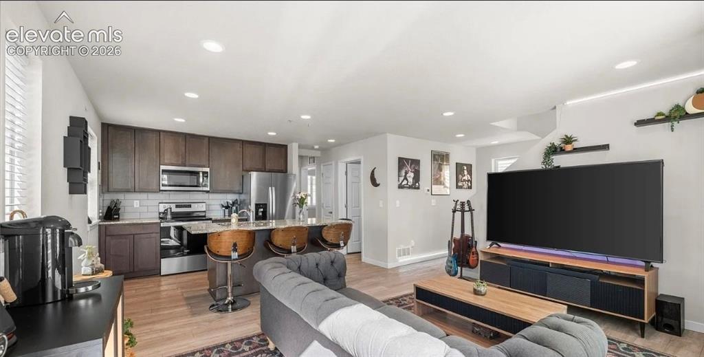 Image 7 of 22: Open-concept living space featuring wood-finish flooring, recessed lighting
