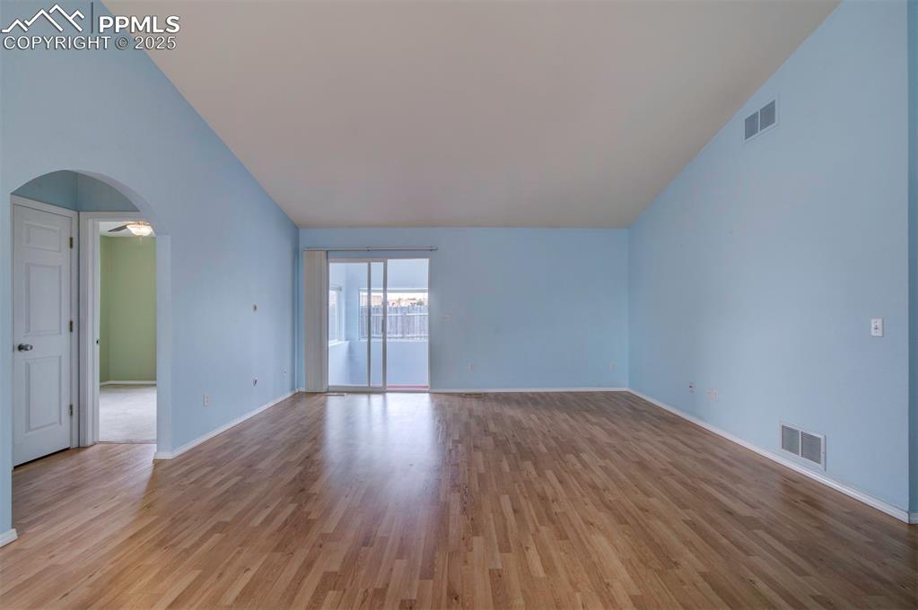Image 10 of 30: Arched walkways, wood style floors, walk out to Sunroom and lofted ceiling
