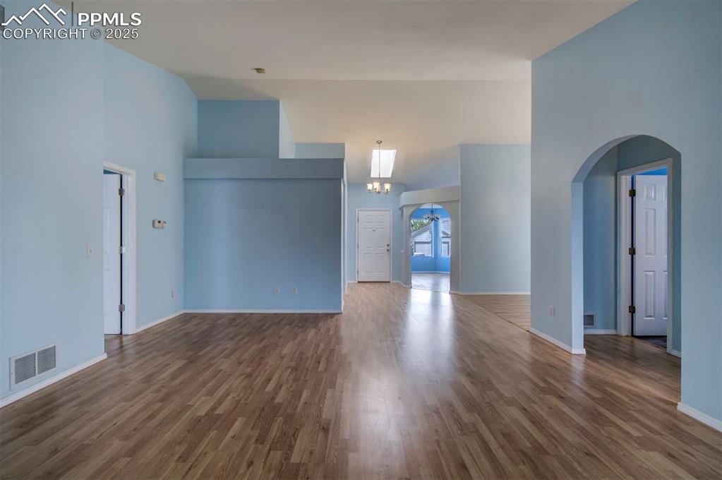 Image 11 of 30: Arched walkways, wood style floors, walk out to Sunroom and lofted ceiling