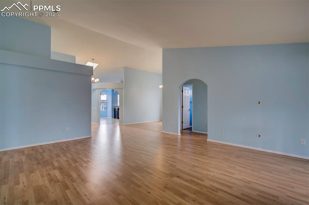 Image 12 of 30: Arched walkways, wood style floors, walk out to Sunroom and lofted ceiling
