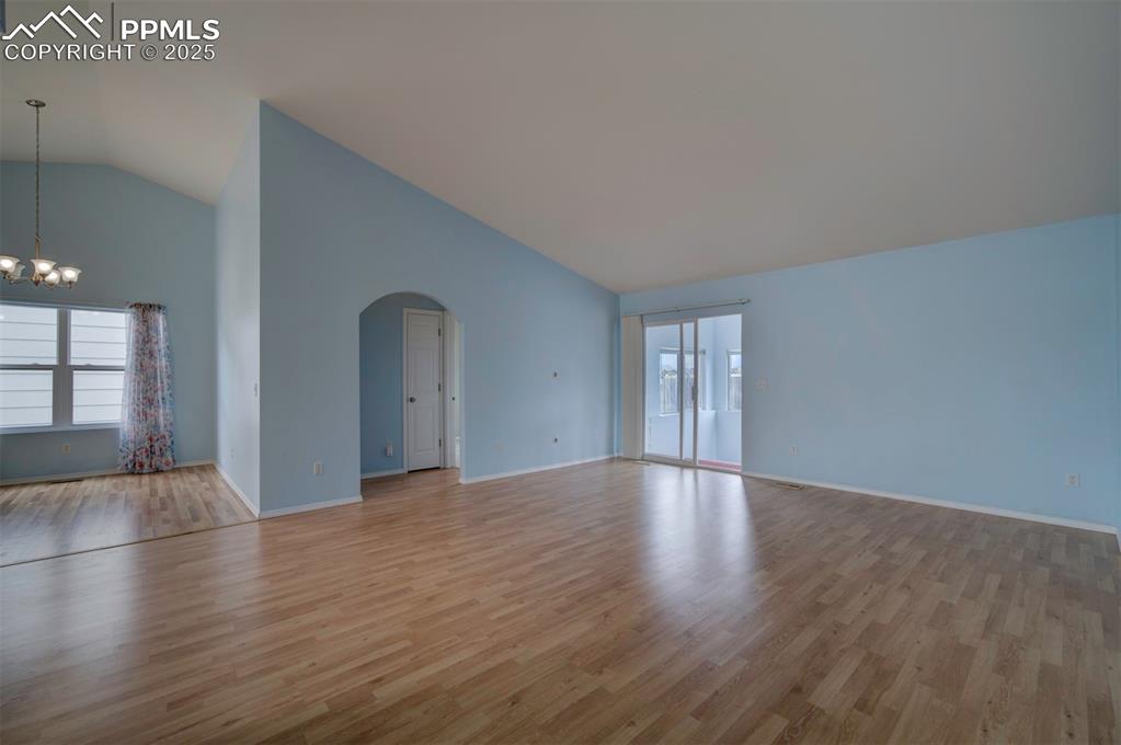 Image 13 of 30: Arched walkways, wood style floors, walk out to Sunroom and lofted ceiling