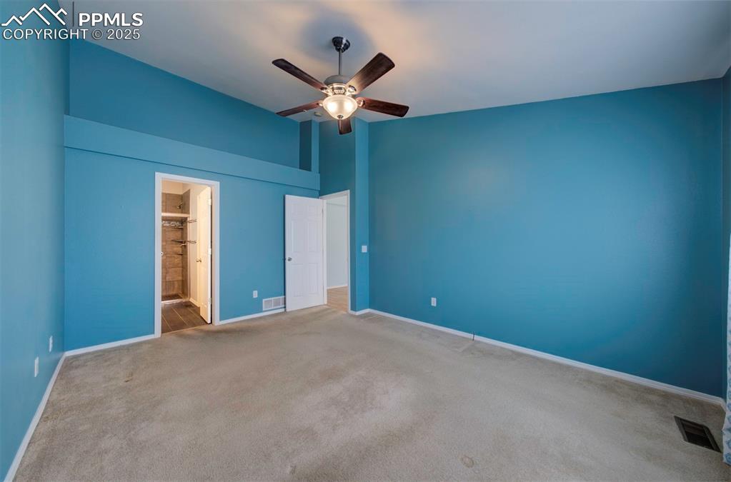 Image 16 of 30: Ceiling Fan, carpet, walk in closet, adjoining bathroom