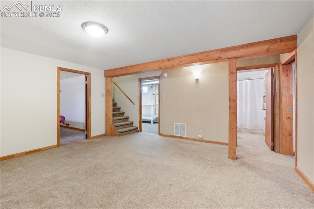 Image 13 of 30: Empty room with stairs, light colored carpet, and a textured ceiling