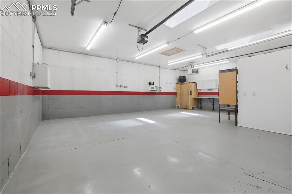 Image 22 of 30: Garage featuring a garage door opener and concrete block wall