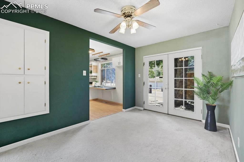 Image 4 of 30: Doorway featuring french doors, carpet floors, and a ceiling fan