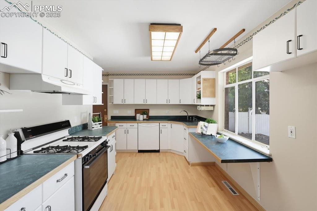 Image 5 of 30: Kitchen with white appliances, white cabinetry, open shelves, and light woo