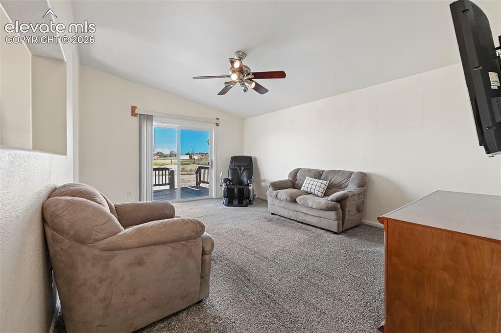 Image 13 of 50: Living area featuring high ceilings, neutral wall tones, plush wall-to-wall