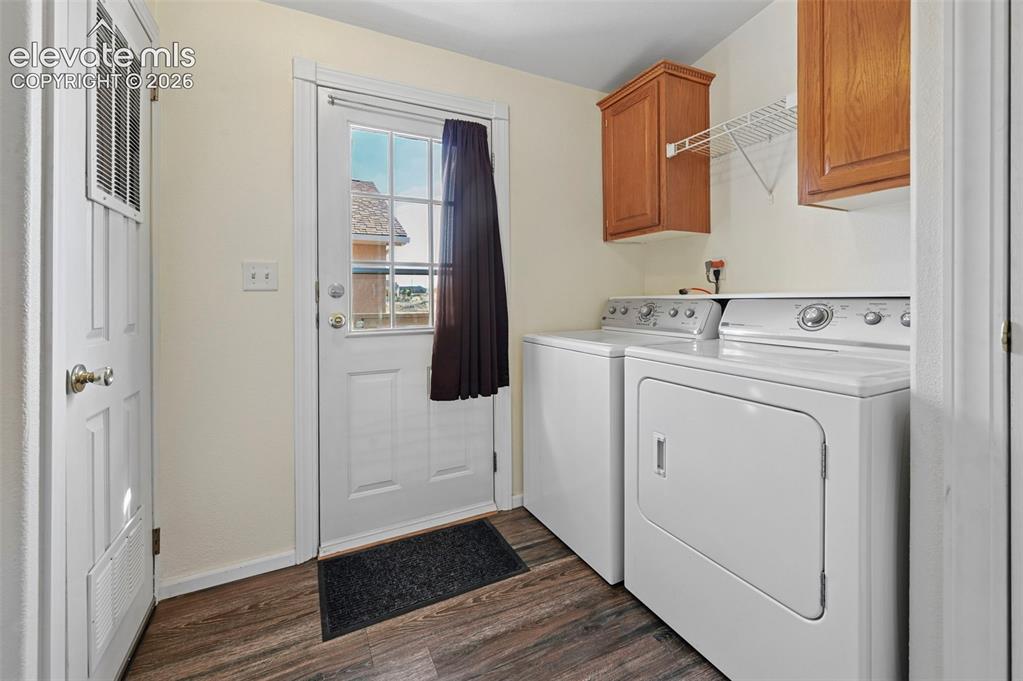 Image 14 of 50: Laundry area featuring wood-finish flooring, upper wooden cabinetry, wire s