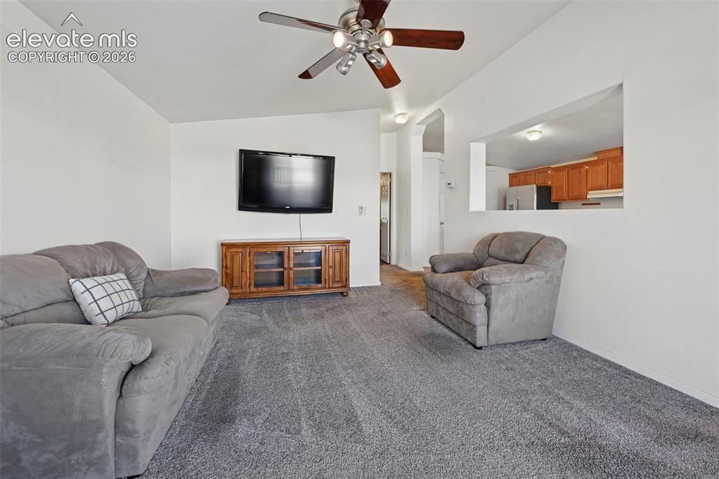 Image 17 of 50: Living area featuring neutral carpeting, a ceiling fan with multi-light fix