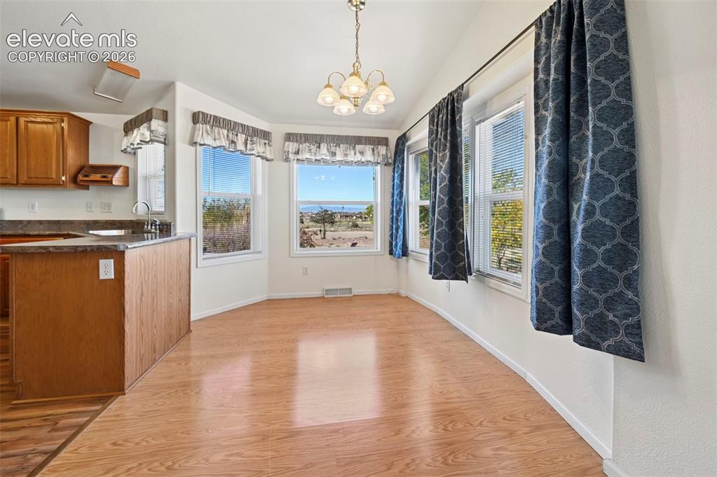 Image 19 of 50: Dining area featuring wood-finish flooring, a multi-arm chandelier, multipl