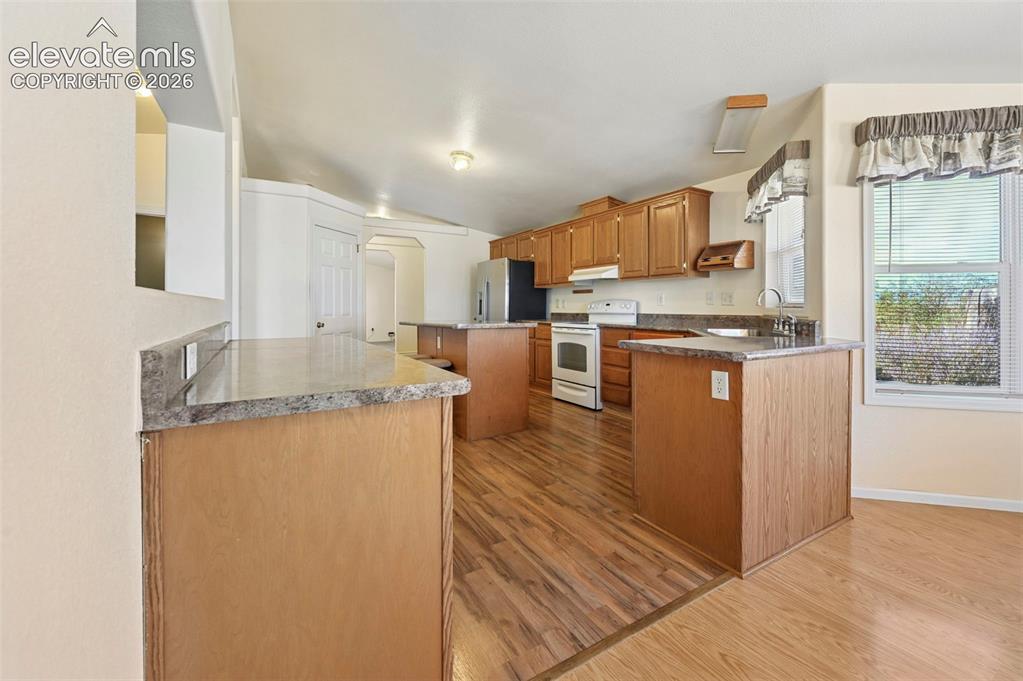 Image 20 of 50: Kitchen featuring wood cabinetry, laminate countertops, a central island, a