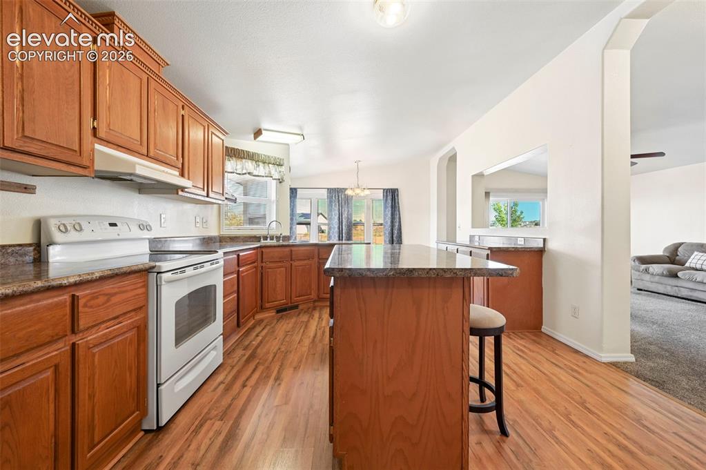 Image 23 of 50: Kitchen featuring wood cabinetry, a central island with a stone-finish coun