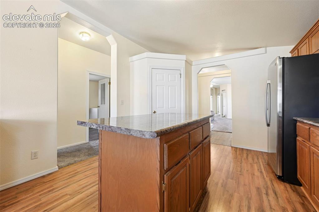 Image 25 of 50: Kitchen featuring a center island with a stone-finish countertop, wood-fini