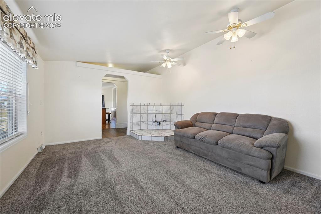 Image 28 of 50: Living space featuring neutral carpeting, dual ceiling fans, and a tiled co
