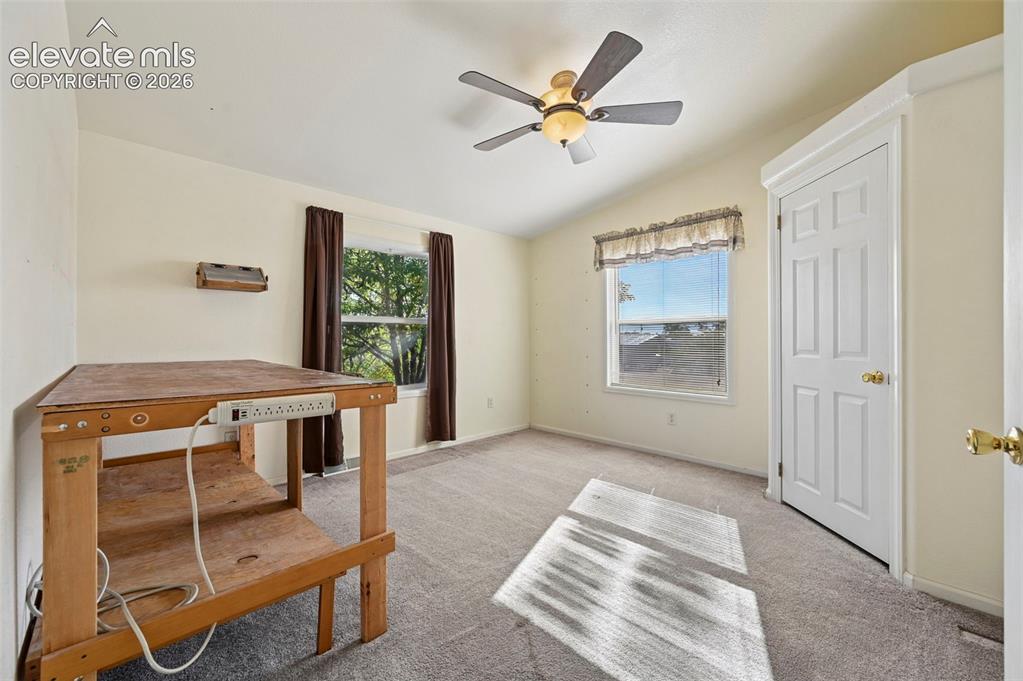 Image 35 of 50: Neutral carpeted flooring, vaulted ceilings, multi-pane windows, and a cent