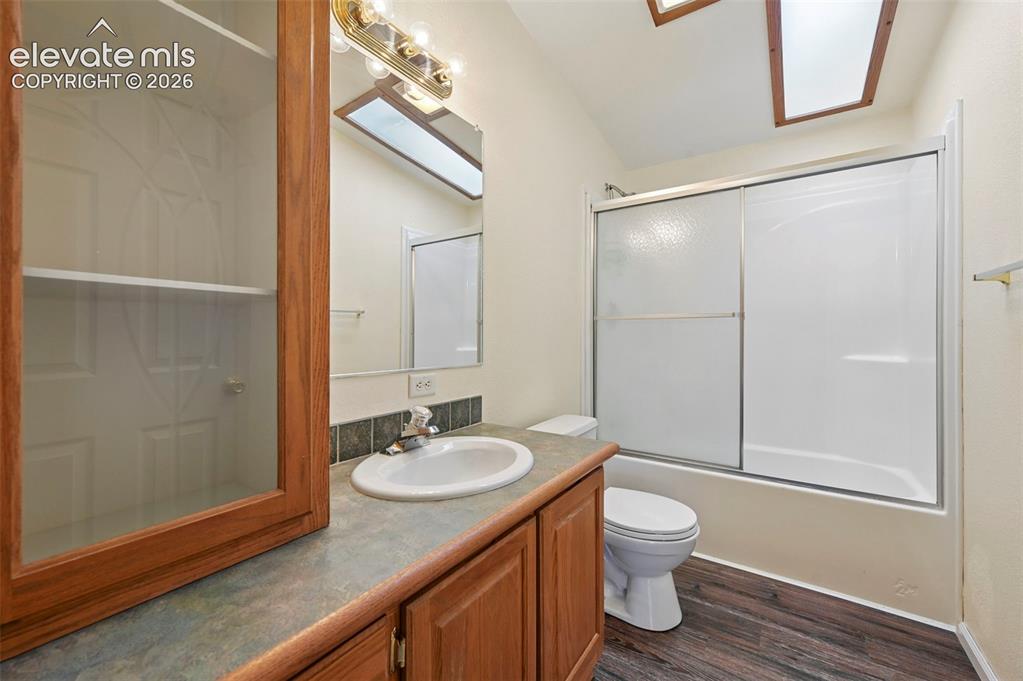 Image 36 of 50: Bathroom featuring wood-finish cabinetry, built-in display shelving, skylig