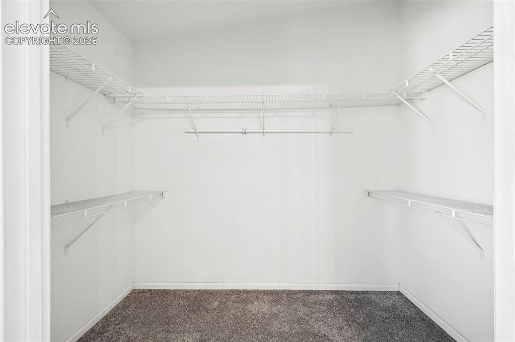 Image 38 of 50: Walk-in closet featuring tiered wire shelving and integrated hanging rods,