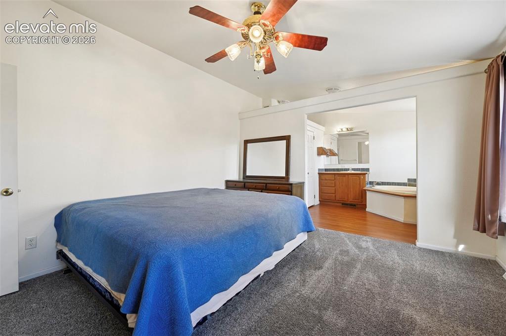 Image 39 of 50: Room featuring carpeted flooring, vaulted ceilings, and a ceiling fan with 