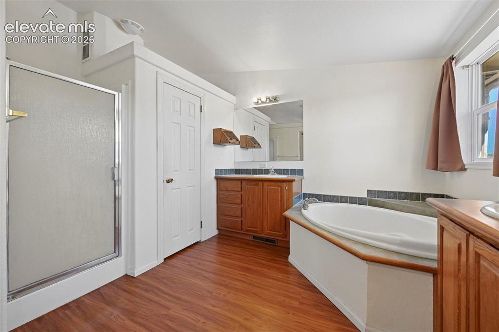 Image 41 of 50: Bathroom featuring wood-finish flooring, a separate walk-in shower with a f