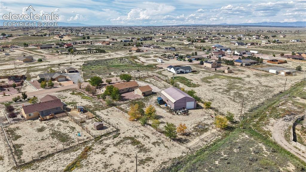 Image 44 of 50: Aerial perspective featuring a detached metal structure, fenced perimeter,